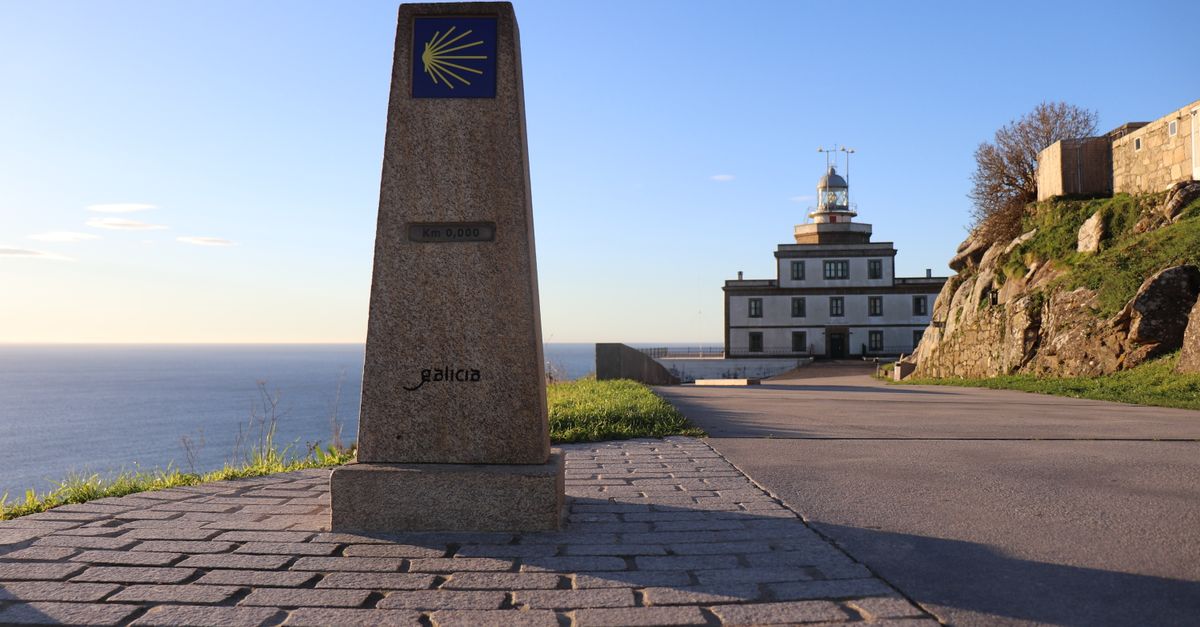 Cabo Fisterra lighthouse under clear blue sky in Galicia, Spain with kilometer zero landmark.